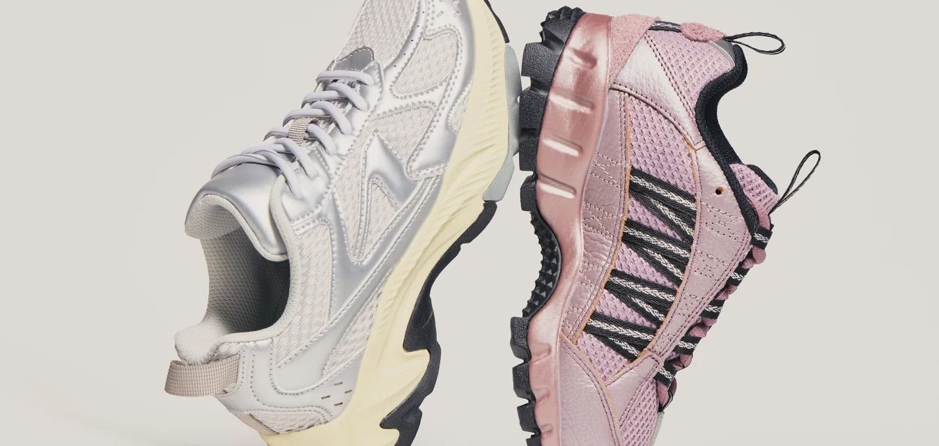Un paio di scarpe da ginnastica, la sinistra metallizzata argento con suola crema, la destra rosa con lacci neri a rete, posizionate sole a sole su uno sfondo neutro.