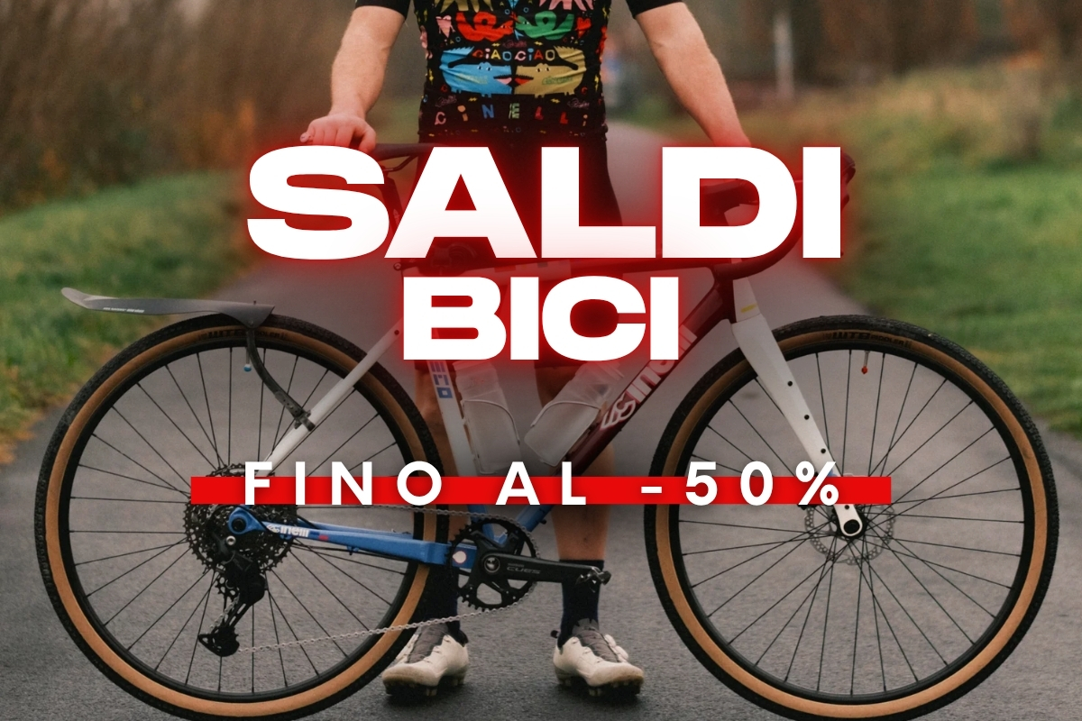 Promotional poster of a person holding a road bike on a path with bold text 'Saldi Bici fino al -50%' advertising bike sale