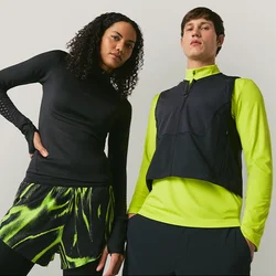 Due modelli posano contro uno sfondo semplice, uno indossa abbigliamento sportivo nero e verde neon, l'altro una maglia nera con giacca verde neon e giubbotto.