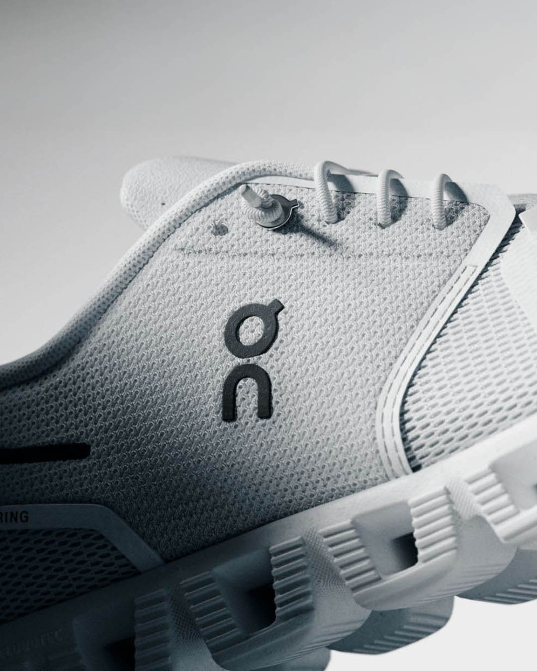 Close-up of white On Cloud running shoe side showing breathable mesh upper, lace, logo and distinctive cushioned CloudTec sole
