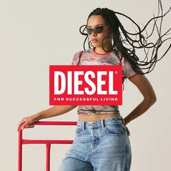Donna con capelli intrecciati e occhiali da sole, che indossa una maglietta grafica e jeans, appoggiata a una struttura metallica rossa contro uno sfondo semplice.