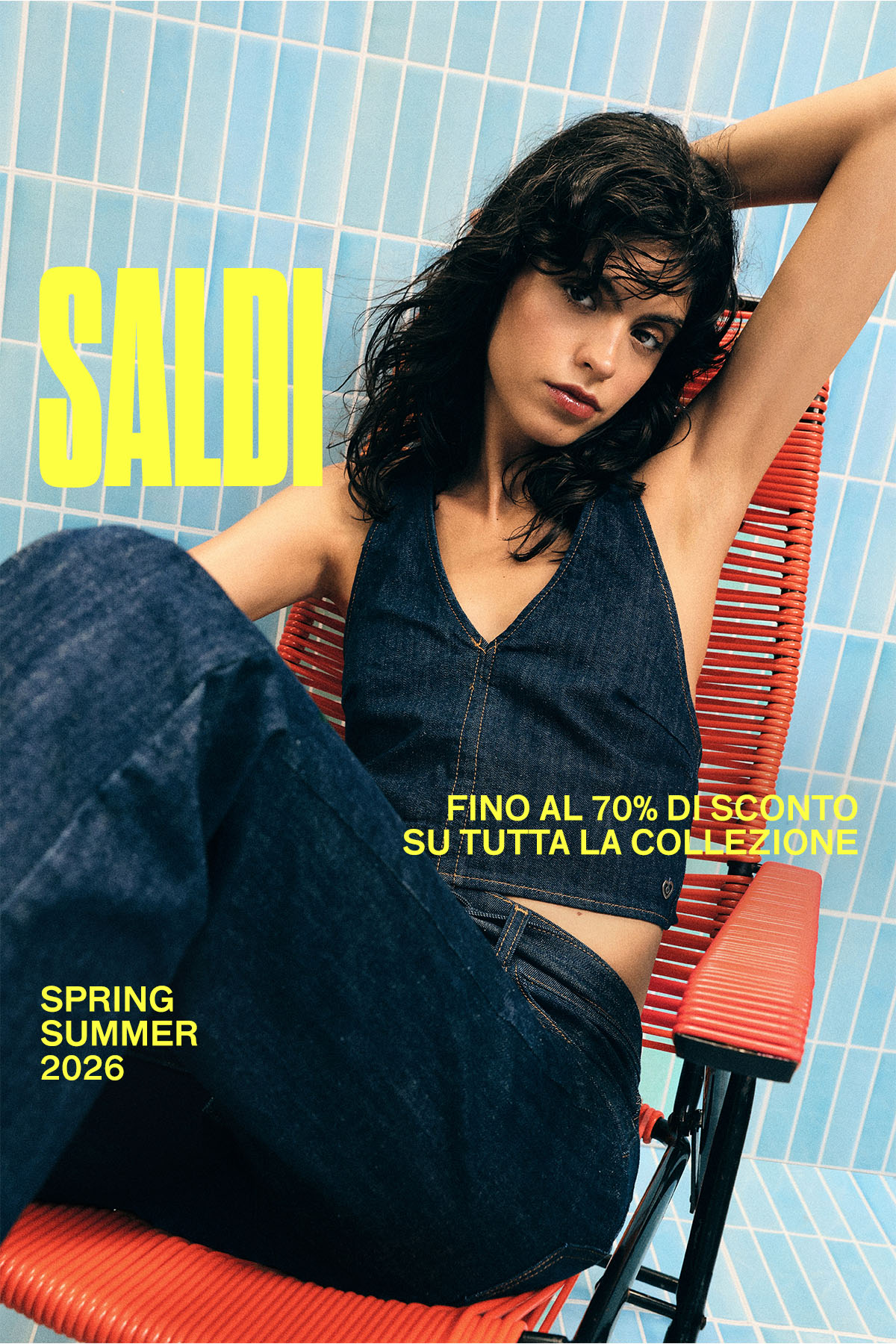 Woman in dark denim two-piece lounging on a red chair against a blue tiled wall with 'SALDI' and 'up to 70% off' sale text