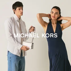 Giovane donna in abito blu navy posa mentre un uomo con camicia bianca e jeans tiene una piccola borsa bianca in una stanza semplice.