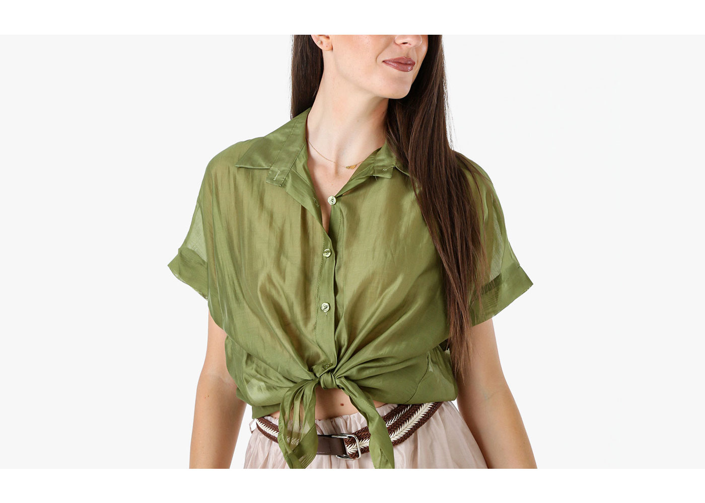 Woman wearing sheer olive-green button-up shirt tied at the waist, long hair, beige skirt with braided belt