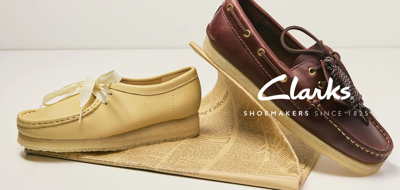 Mocassino color cuoio e scarpa da barca marrone scuro con lacci esposti su un libro contro uno sfondo bianco.
