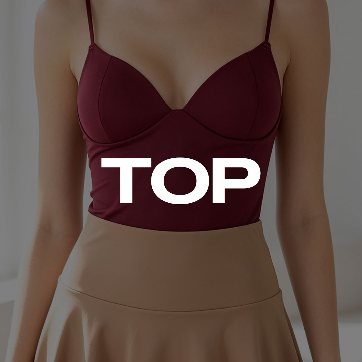 Cropped image of a woman wearing a maroon fitted spaghetti-strap camisole top paired with a high-waisted beige skirt