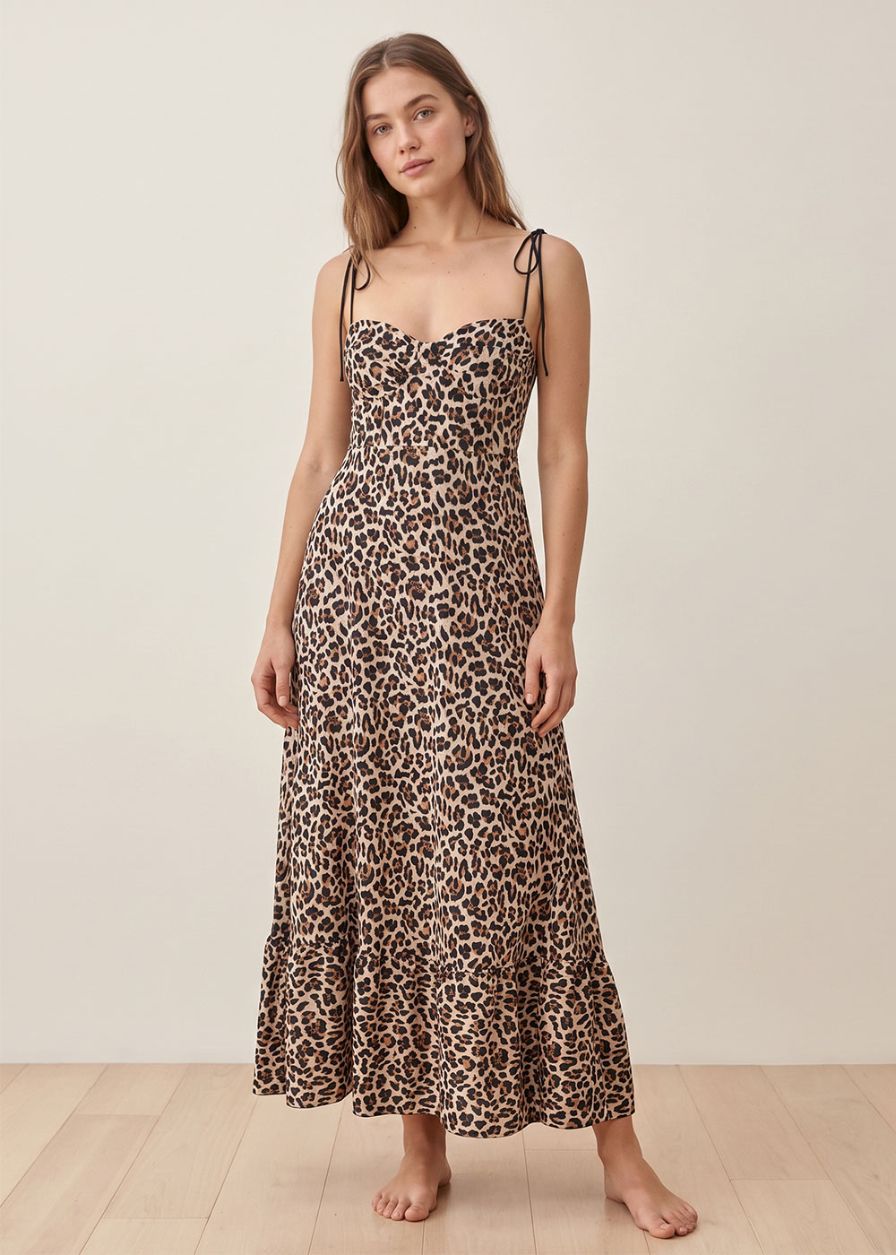 Model wearing leopard-print maxi dress with tie spaghetti straps and sweetheart neckline, standing barefoot on wooden floor