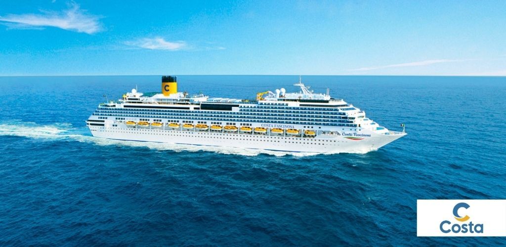 Large white Costa cruise ship sailing on deep blue ocean beneath a clear blue sky, logo visible