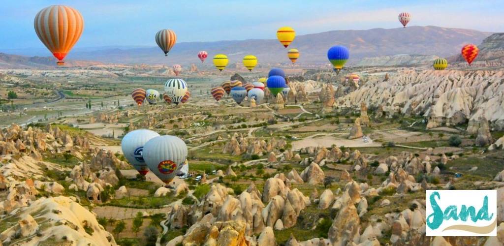 Colourful hot-air balloons floating over Cappadocia's fairy chimneys and rugged valley landscape at sunrise