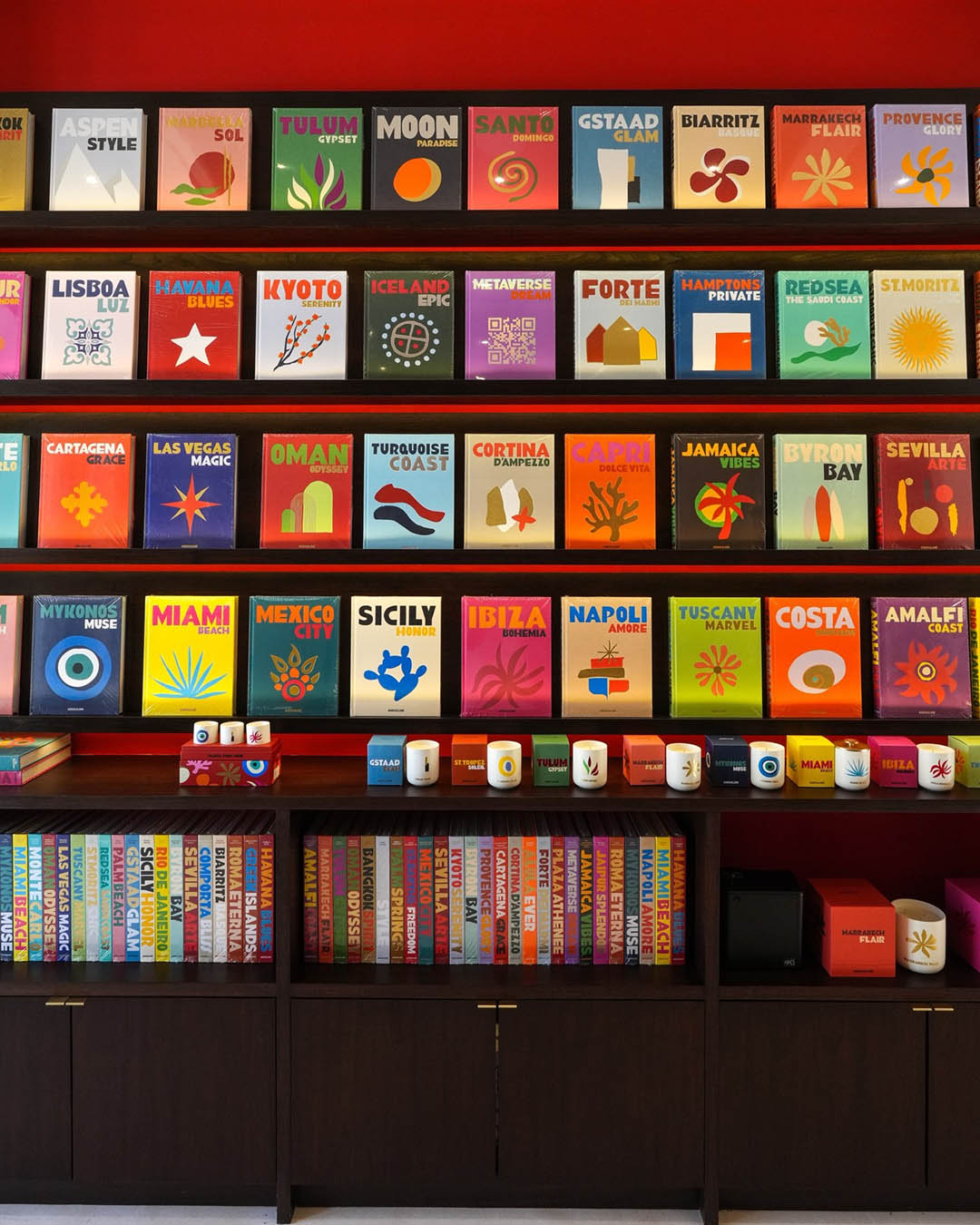 Bright wall of colourful travel posters, destination-themed mugs and guidebooks arranged on wooden shelves