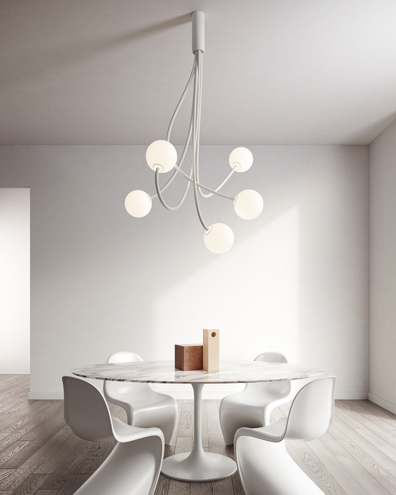 Minimalist dining room with round white marble table, four modern white chairs and sculptural five-globe pendant light in neutral interior