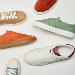 Sneaker casual variopinte in beige, arancione, verde, bianco con accenti rossi, rosa e blu disposte in cerchio su uno sfondo bianco.