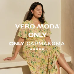 Donna con capelli scuri seduta su una panchina bianca, indossa un vestito giallo a fiori e sandali neri con tacco sotto una luce naturale intensa.