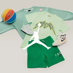 Felpa verde, t-shirt grafica verde chiaro, pantaloncini verdi, due scarpe da ginnastica bianche e un pallone da basket Nike arancione e blu su uno sfondo chiaro.