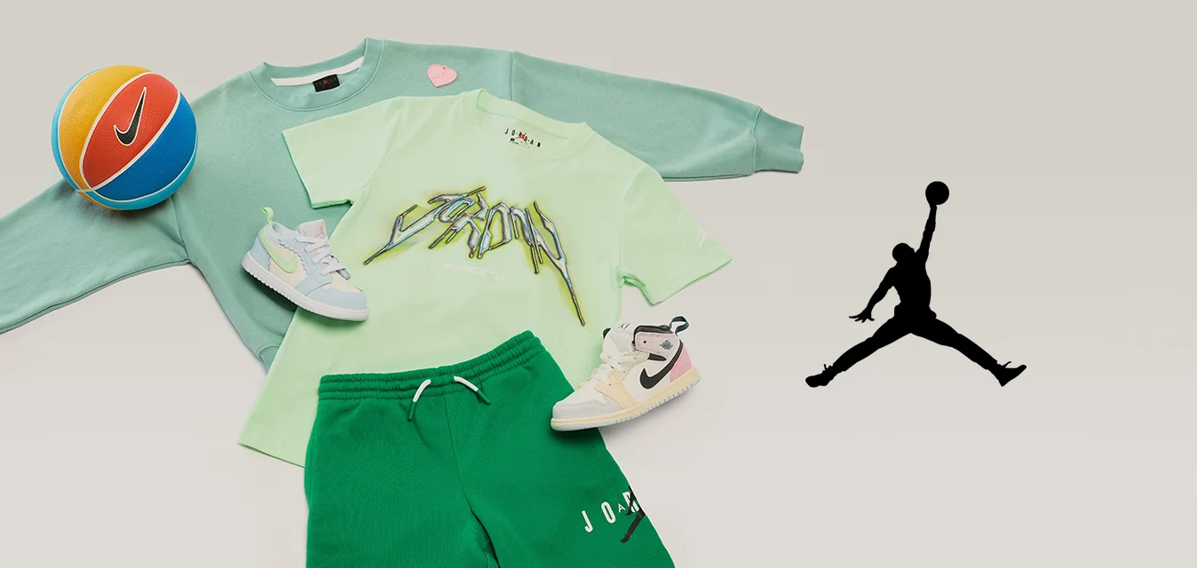 Felpa verde, t-shirt grafica verde chiaro, pantaloncini verdi, due scarpe da ginnastica bianche e un pallone da basket Nike arancione e blu su uno sfondo chiaro.