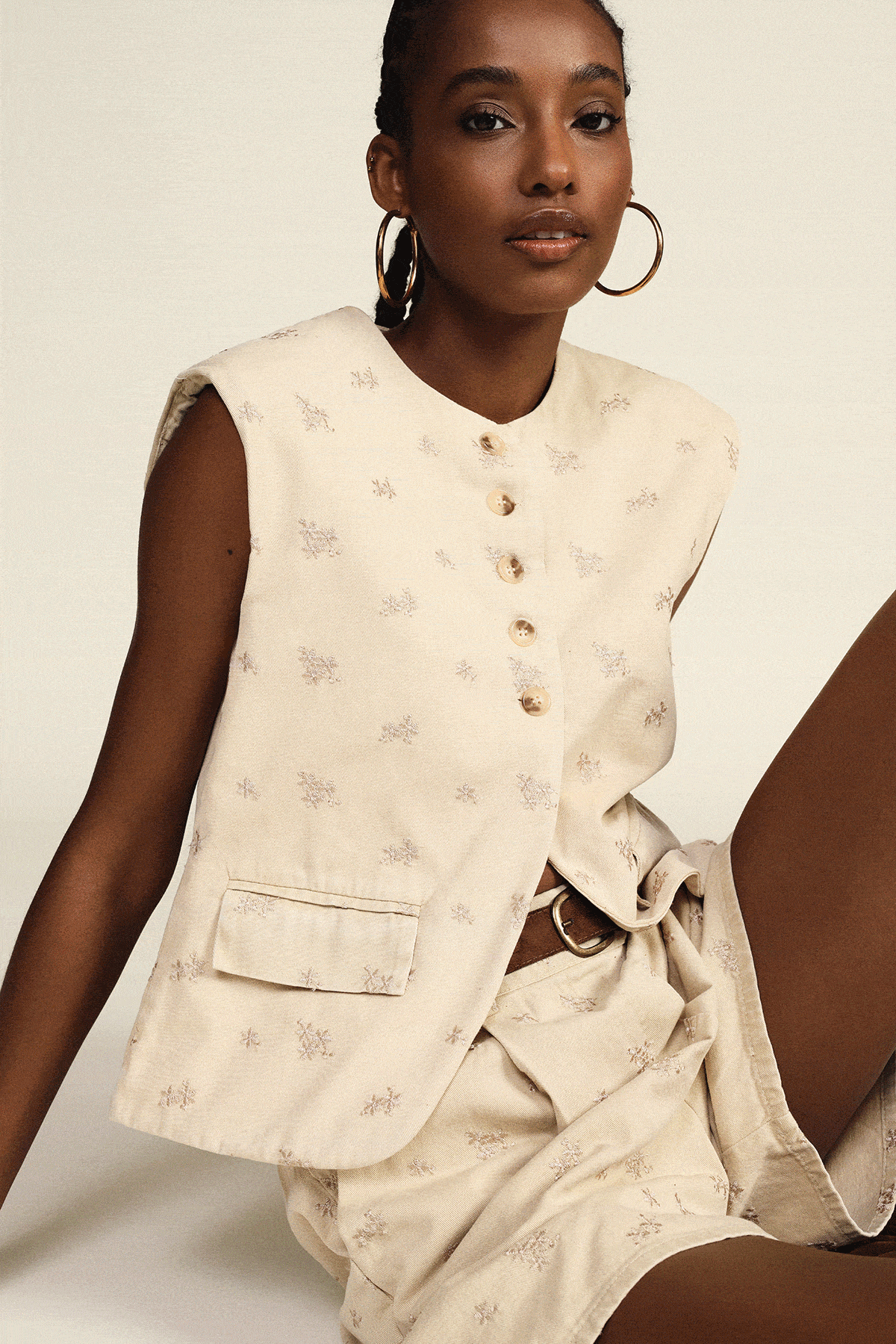 Collage of four women's summer outfits: cream embroidered waistcoat with shorts, olive sleeveless vest, herringbone blazer suit, brown polka‑dot peplum top