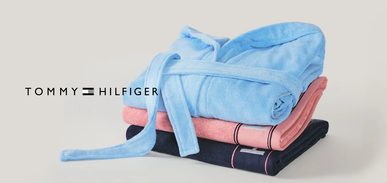 Pila di tre abiti piegati nei colori blu, rosa e blu scuro con una cintura legata su sfondo chiaro.