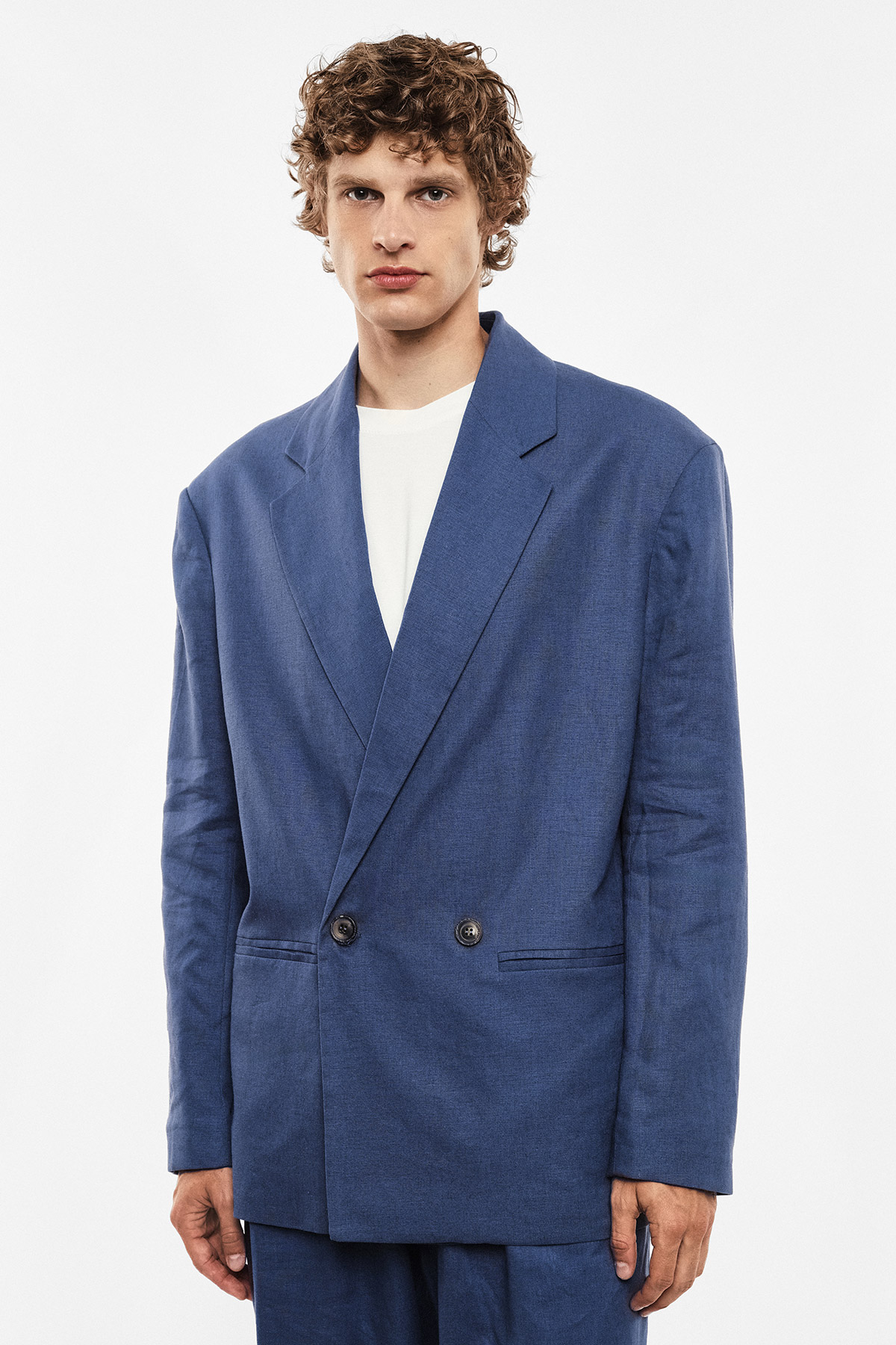 Model wearing oversized blue double-breasted blazer over white T-shirt against plain white background