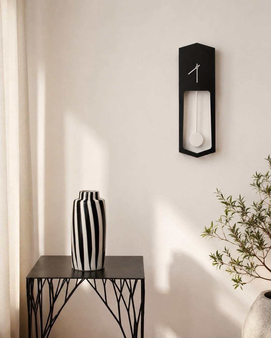 Minimalist corner with black pendulum wall clock, striped black-and-white vase on metal side table and potted plant