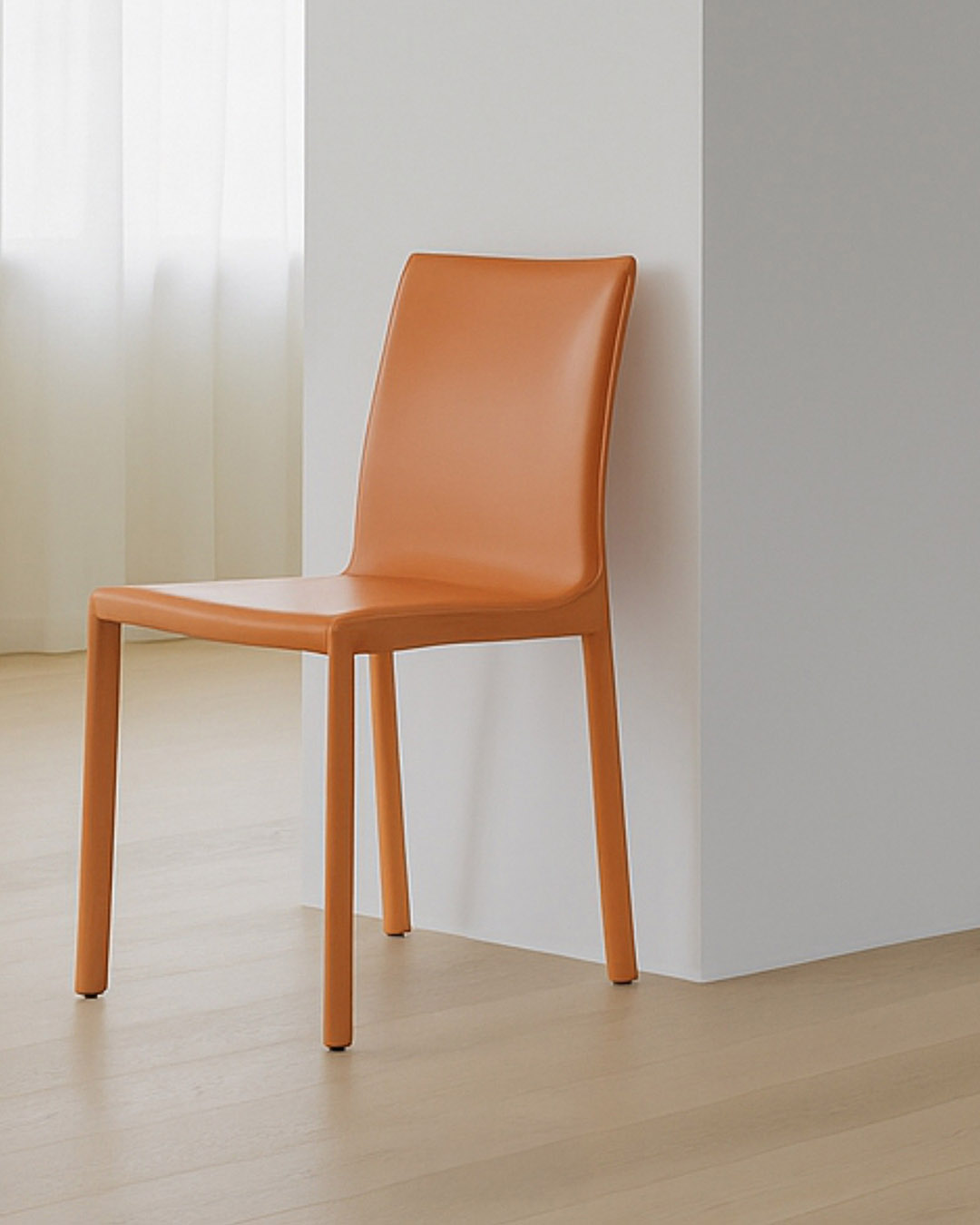 Orange modern plastic dining chair with slim legs against a white wall in a minimalist room with light wood floor and sheer curtains