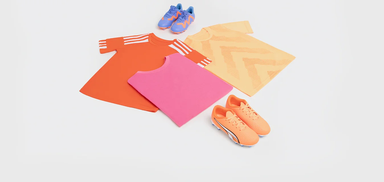 Tre t-shirt di colore arancione, rosa e giallo con motivi, più scarpe sportive blu e arancioni in basso. Il tessuto sembra liscio e leggero.