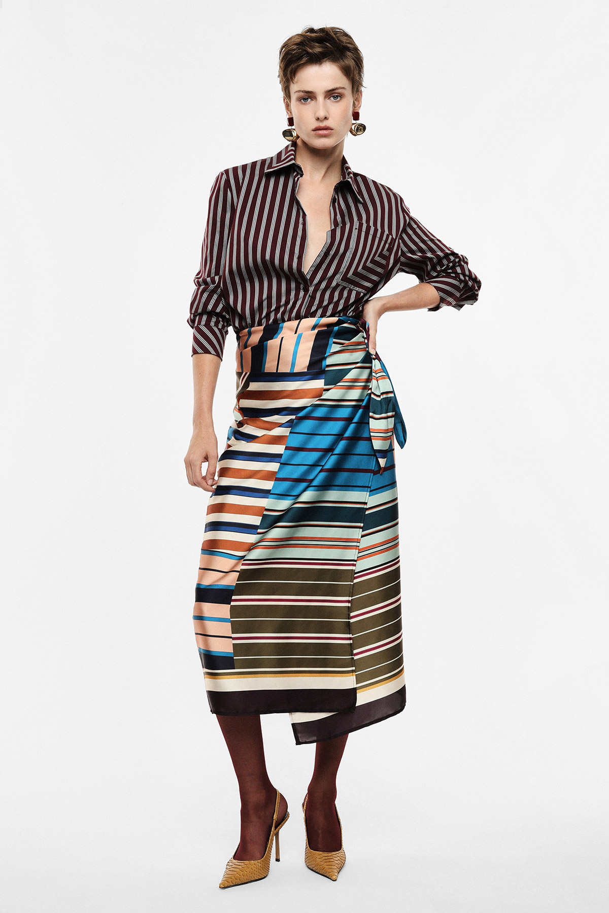 Woman modelling: maroon striped shirt, multicoloured striped wrap midi skirt, maroon tights, yellow heels and statement earrings
