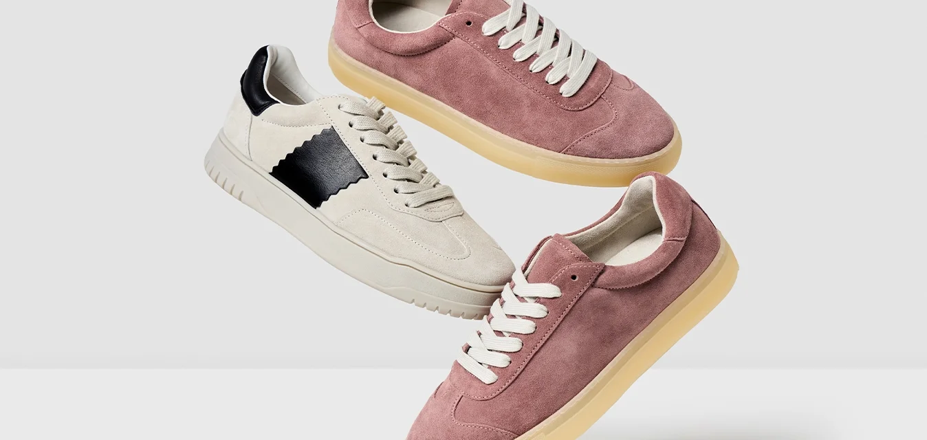 Tre paia di sneakers esposti: un paio rosa in suede, un paio cremisi in suede con un accento nero e una suola in gomma beige.