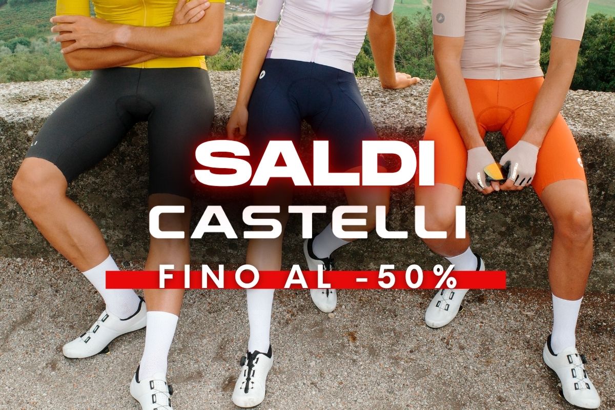 Three cyclists sitting on a stone wall wearing Castelli cycling kits and shoes, promotional text ‘Saldi Castelli fino al -50%’ advertising up to 50% off