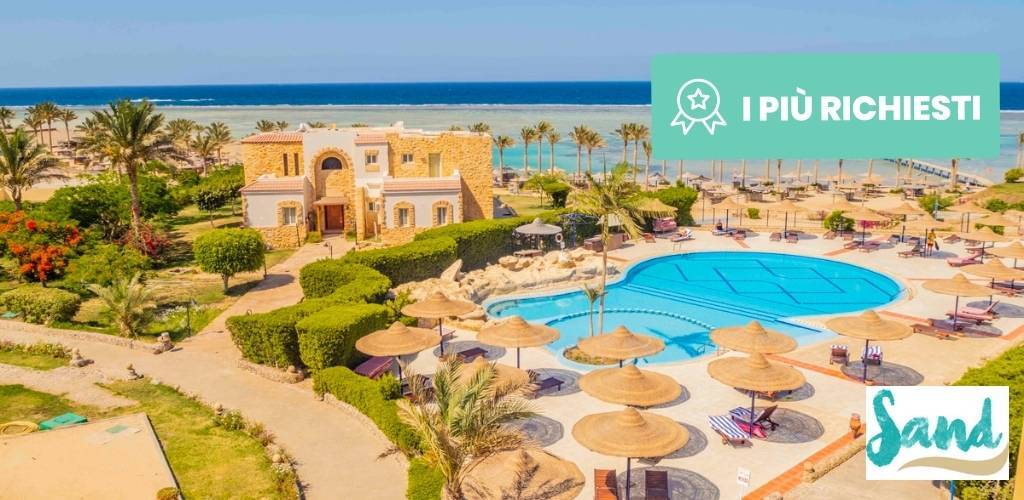 Aerial view of a beachfront resort with circular pool, straw parasols, sunloungers, palm trees and sandy beach by turquoise sea