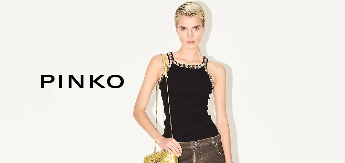 Top nero senza maniche con spalline decorative, jeans a gamba larga marroni con risvolti, e una borsa dorata. Tacchi a strisce neri completano l'outfit.