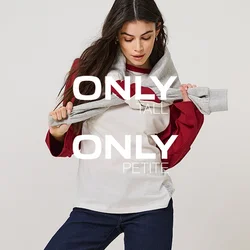 Donna che indossa una maglia a maniche lunghe bianca e rossa, jeans blu scuro con risvolti, scarpe nere, tiene una felpa grigia appoggiata sulle spalle.