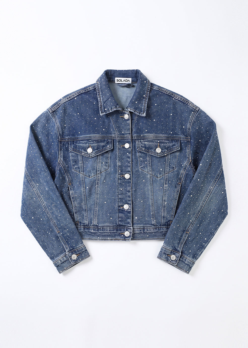 Cropped blue denim jacket with silver stud embellishments, button-front and flap chest pockets, laid flat on white background
