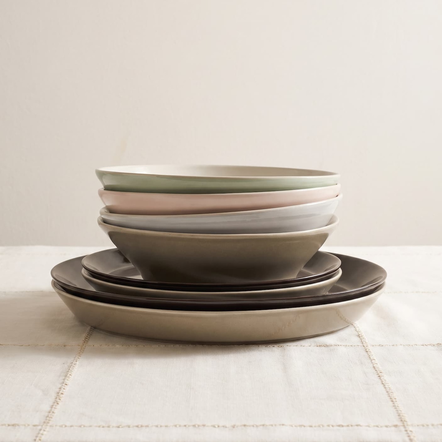 A stack of colorful bowls and plates on a white shelf.