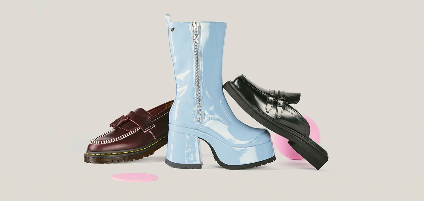 Tre scarpe da donna esposte su uno sfondo neutro: mocassino bordeaux, stivale platform in vernice azzurro chiaro e mocassino nero appoggiato su una palla rosa.