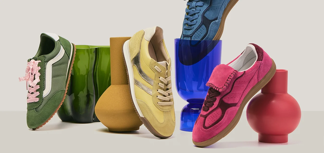 Quattro sneaker colorate in verde, giallo, blu e rosa disposte su vasi di forme uniche nei colori verde, marrone, blu e rosso.