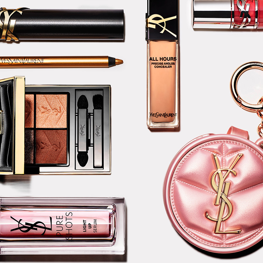 Una selezione dall'alto di cosmetici YSL, tra cui una palette occhi, rossetto, correttore e una pochette rosa trapuntata.