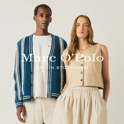 Un uomo con pantaloni chiari, camicia bianca e cardigan a righe blu sta accanto a una donna con top beige senza maniche e gonna lunga con scarpe da ginnastica.