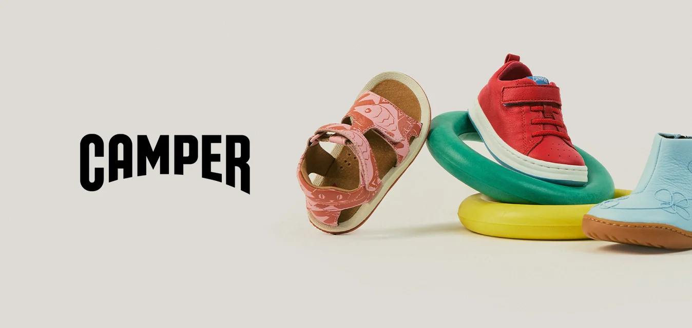 Quattro scarpe da bambino in diversi stili e colori disposte con anelli colorati su uno sfondo neutro.