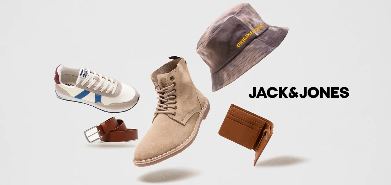 Stivaletti alla caviglia in suede marrone, sneakers bianche con dettagli blu e rossi, un cappello a secchiello grigio, una cintura marrone e un portafoglio marrone, tutti fluttuanti.
