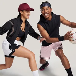 Uomo e donna che giocano a basket, uomo che palleggia, donna in posizione difensiva, entrambi indossano abbigliamento sportivo e scarpe da ginnastica.