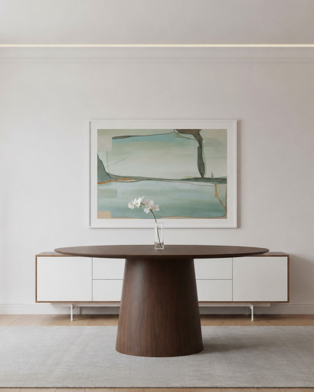 Minimalist dining room with round walnut table, single white orchid in glass vase at centre, white sideboard and teal abstract wall art