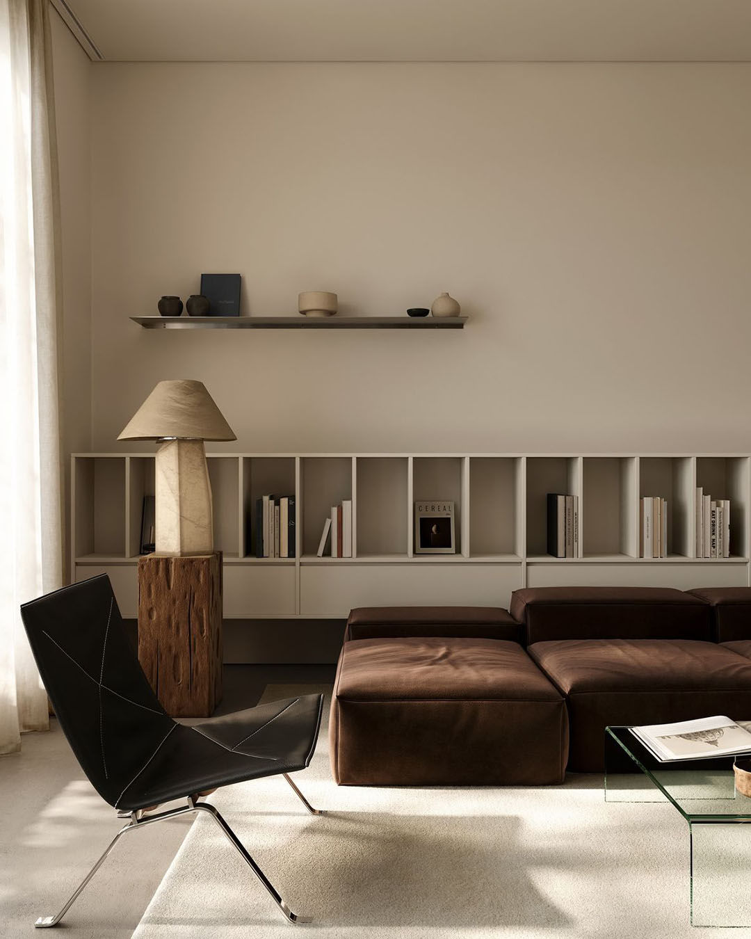 Minimalist living room with brown modular sofa, black lounge chair, wooden lamp, low bookshelf and glass coffee table