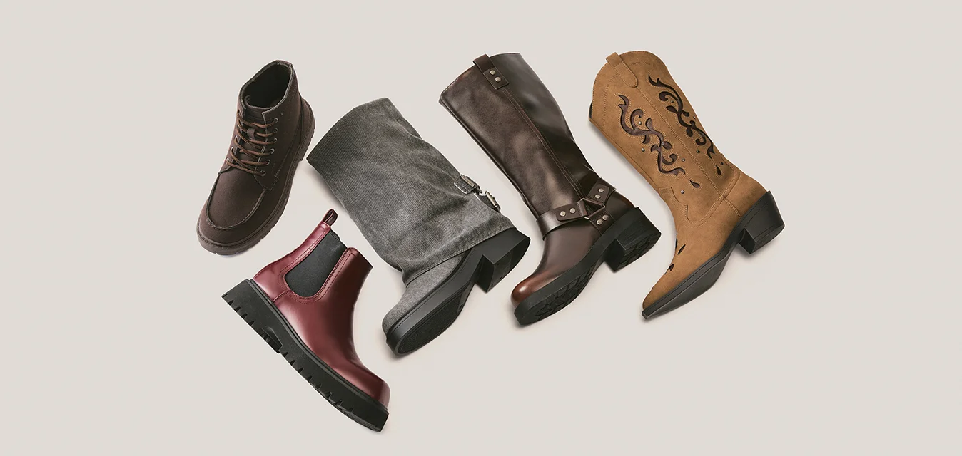 Cinque diversi stivali disposti in fila: marrone da trekking, rosso Chelsea, grigio scamosciato, pelle marrone scuro e cowboy beige con disegni neri.