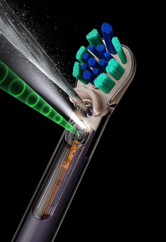 Lo spazzolino Dyson CameraJet accanto a un volto sorridente.