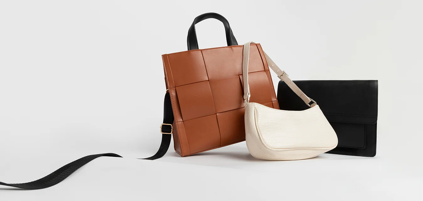 Tre borse: una borsa a tracolla marrone a motivo quadrato, una borsa bianca a spalla con texture e una elegante clutch nera con design piatto e senza hardware visibile.