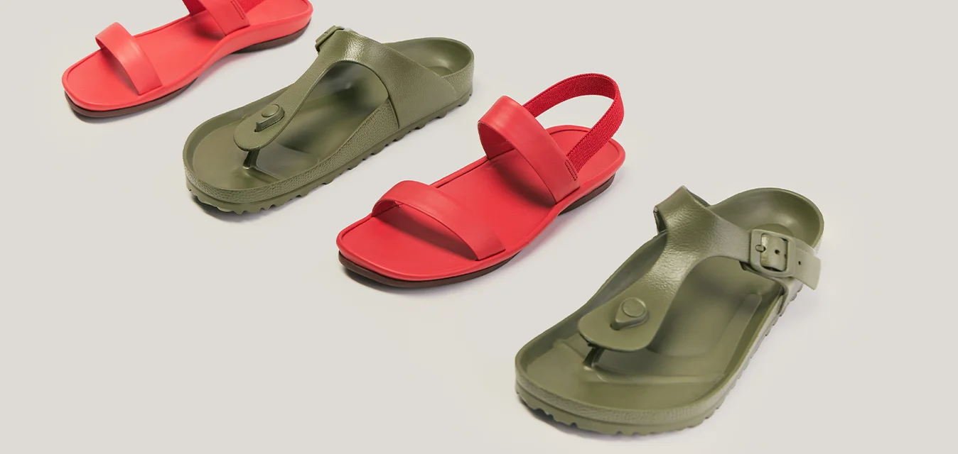 Due paia di sandali, uno rosso e uno verde oliva, disposti in colori alternati su uno sfondo chiaro e semplice.