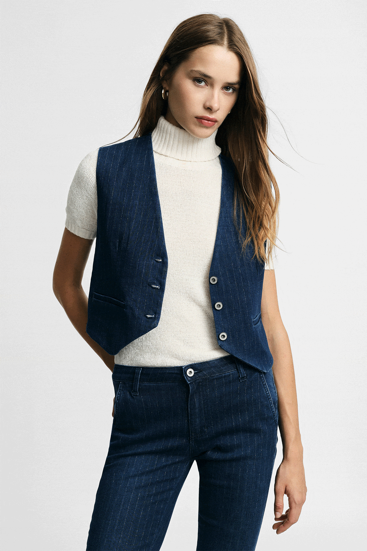 Woman modelling navy denim waistcoat and matching trousers with white short-sleeve roll-neck top, four studio poses on white background