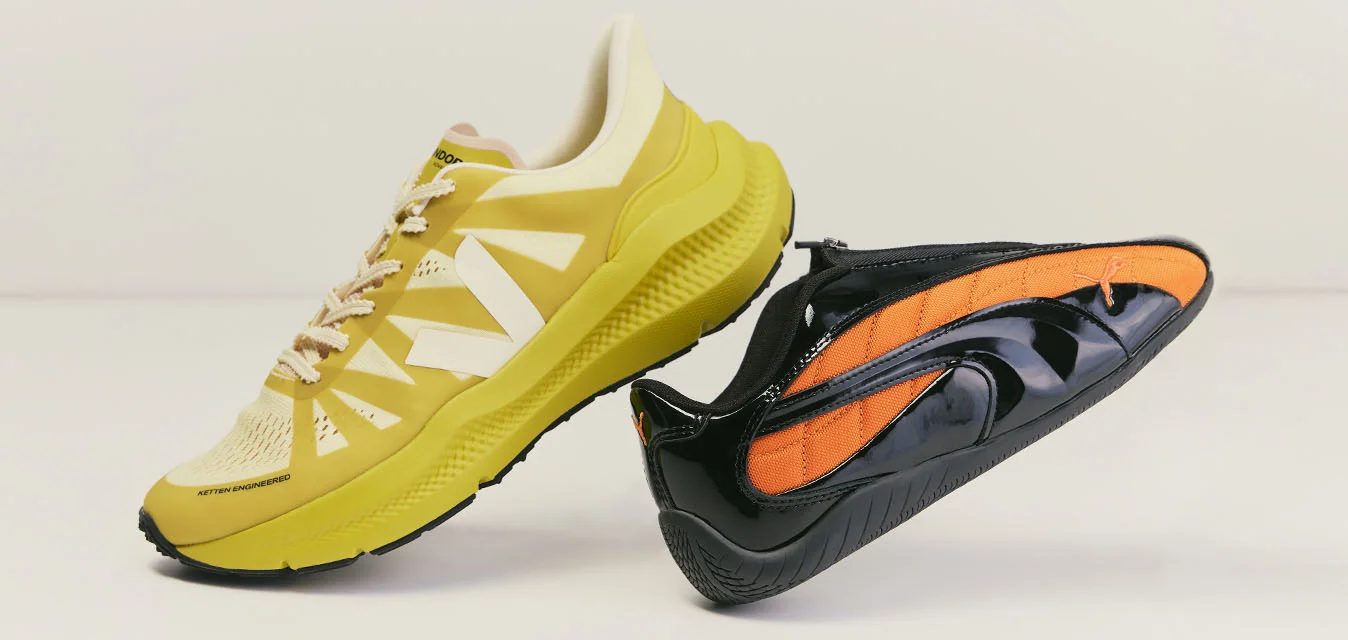 Scarpa da running gialla e sneaker nera slip-on con dettagli arancioni posizionate fianco a fianco su uno sfondo chiaro e semplice.