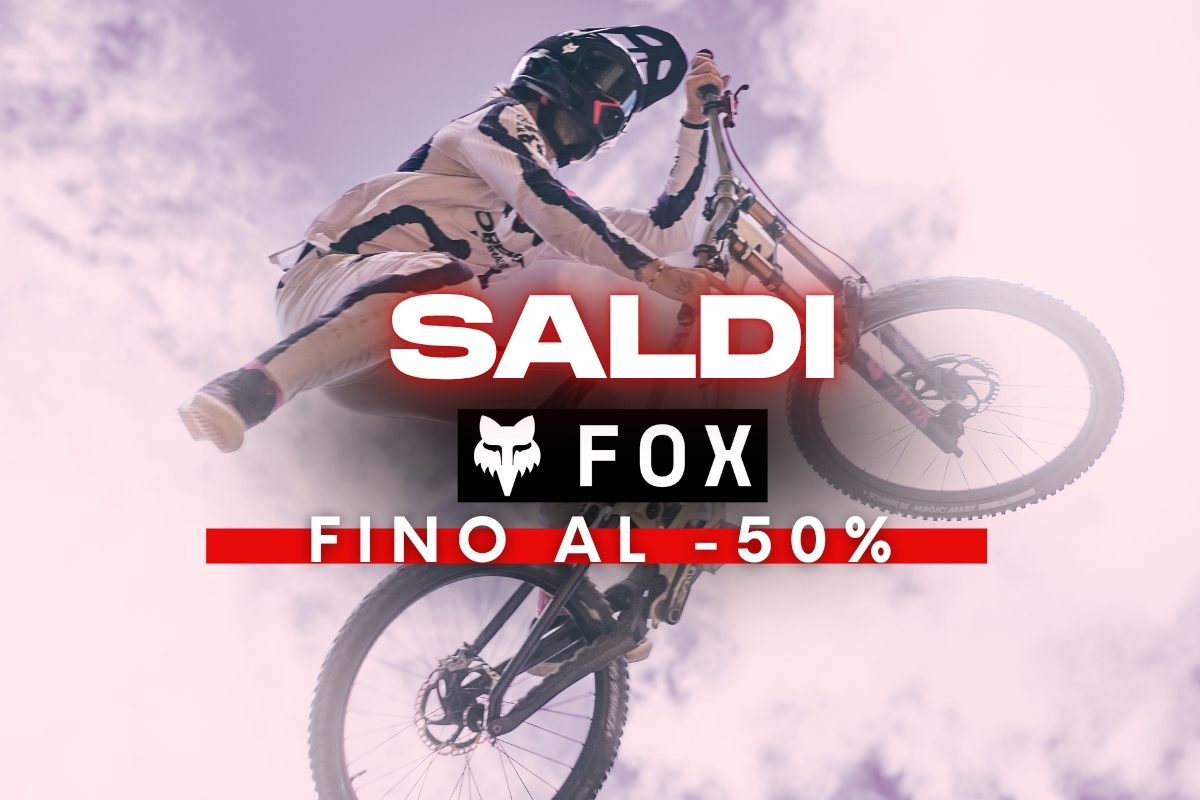 Mountain biker performing an airborne jump with FOX logo and 'SALDI' banner, promotional sale on biking gear up to 50% off