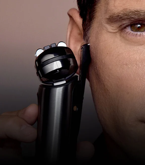 Primo piano del viso di un uomo con il rasoio Braun NEVO e il rifinitore integrato per peli lunghi in uso